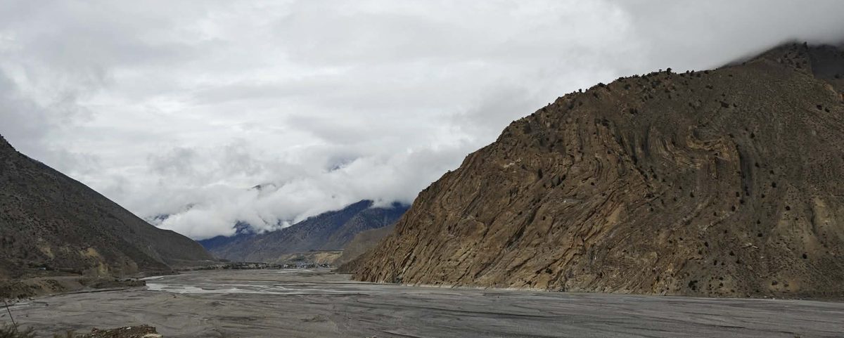 Riders crossing ochre high-desert terrain on the Upper Mustang corridor